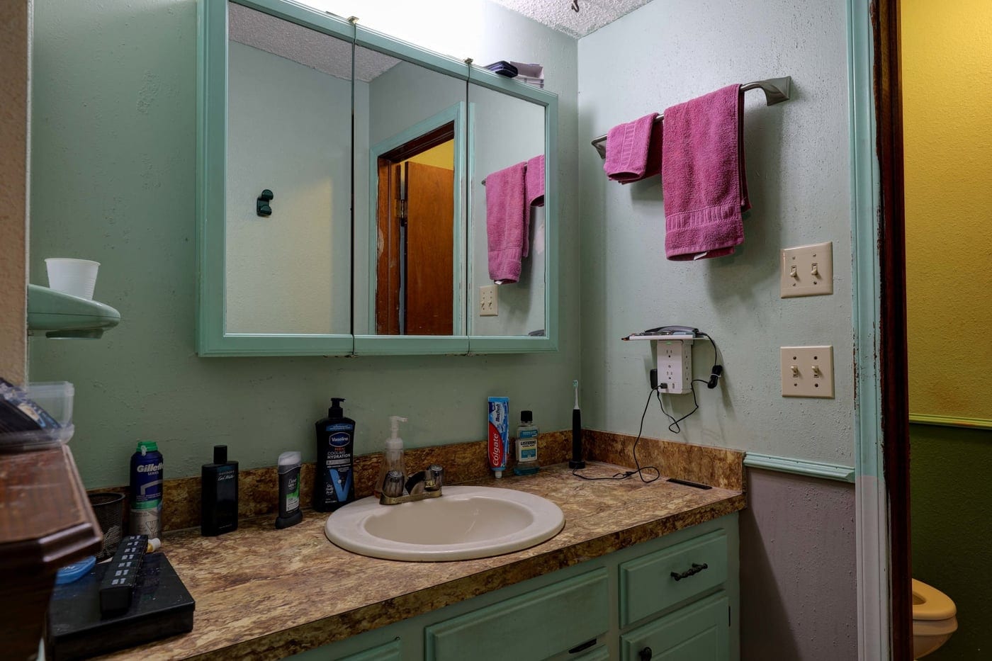 Dated green vanity and laminate countertop before the remodel