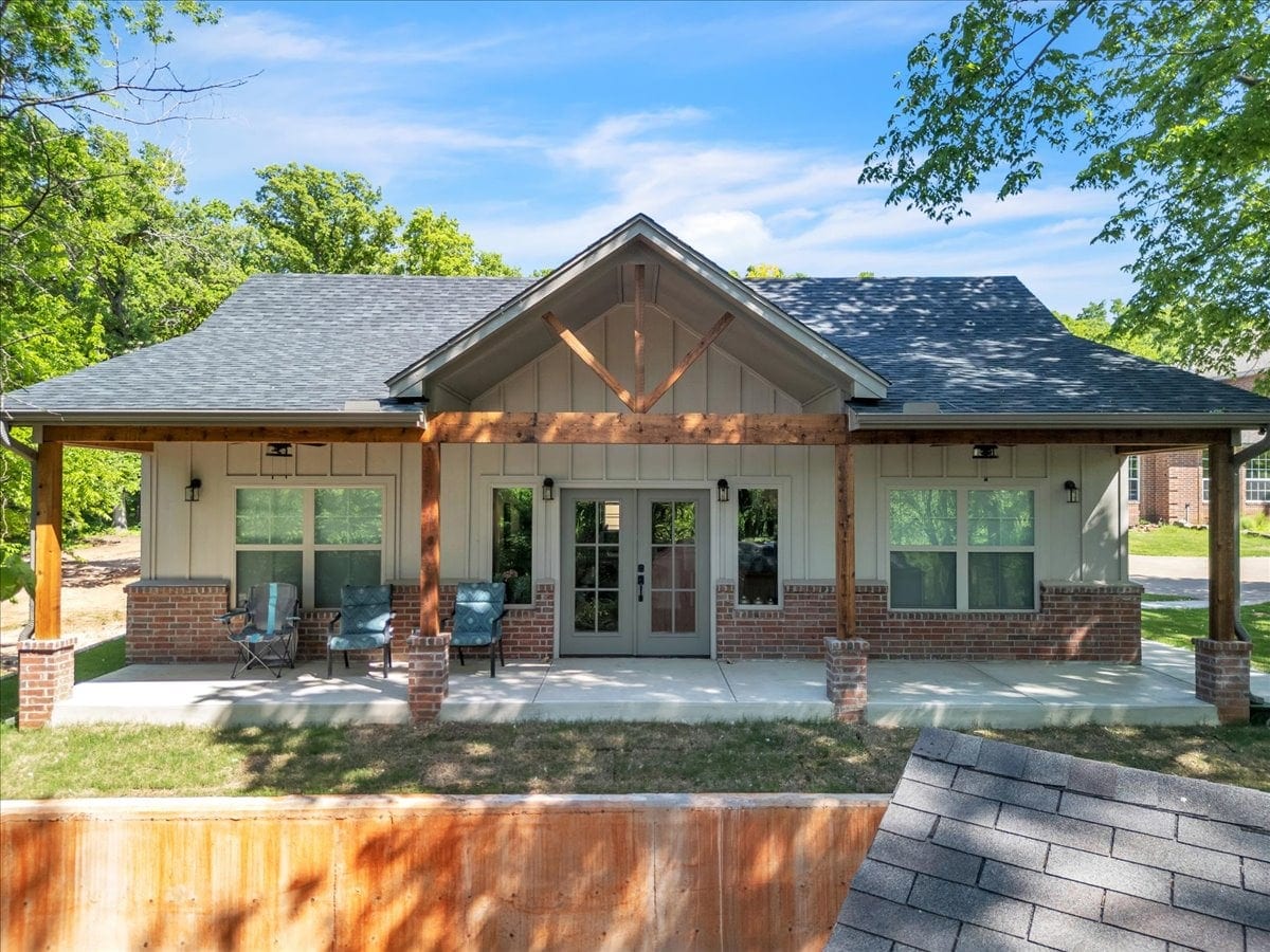 Detached guest house with covered porch, board-and-batten siding and brick wainscot