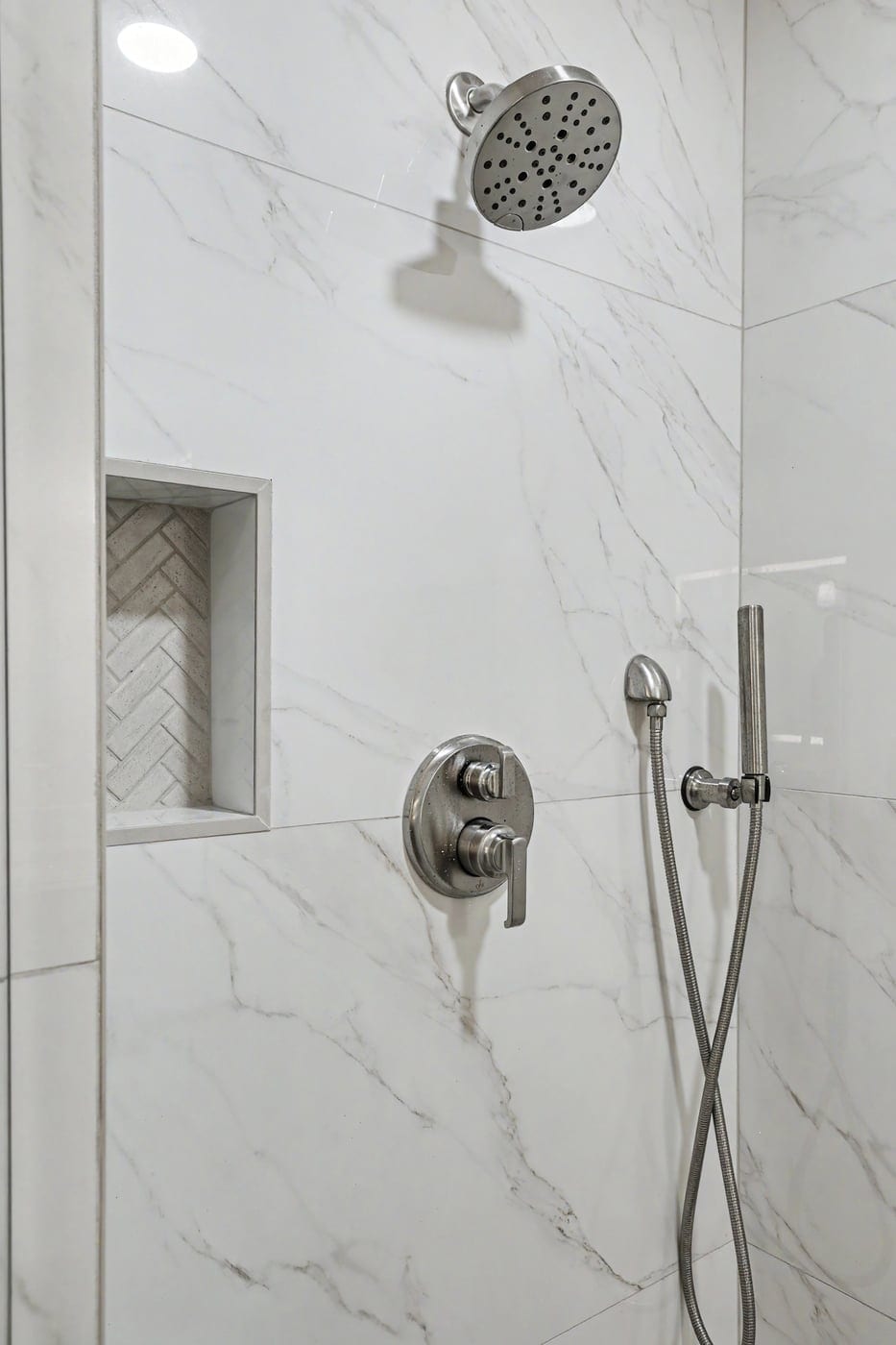 Shower niche with herringbone tile and handheld shower